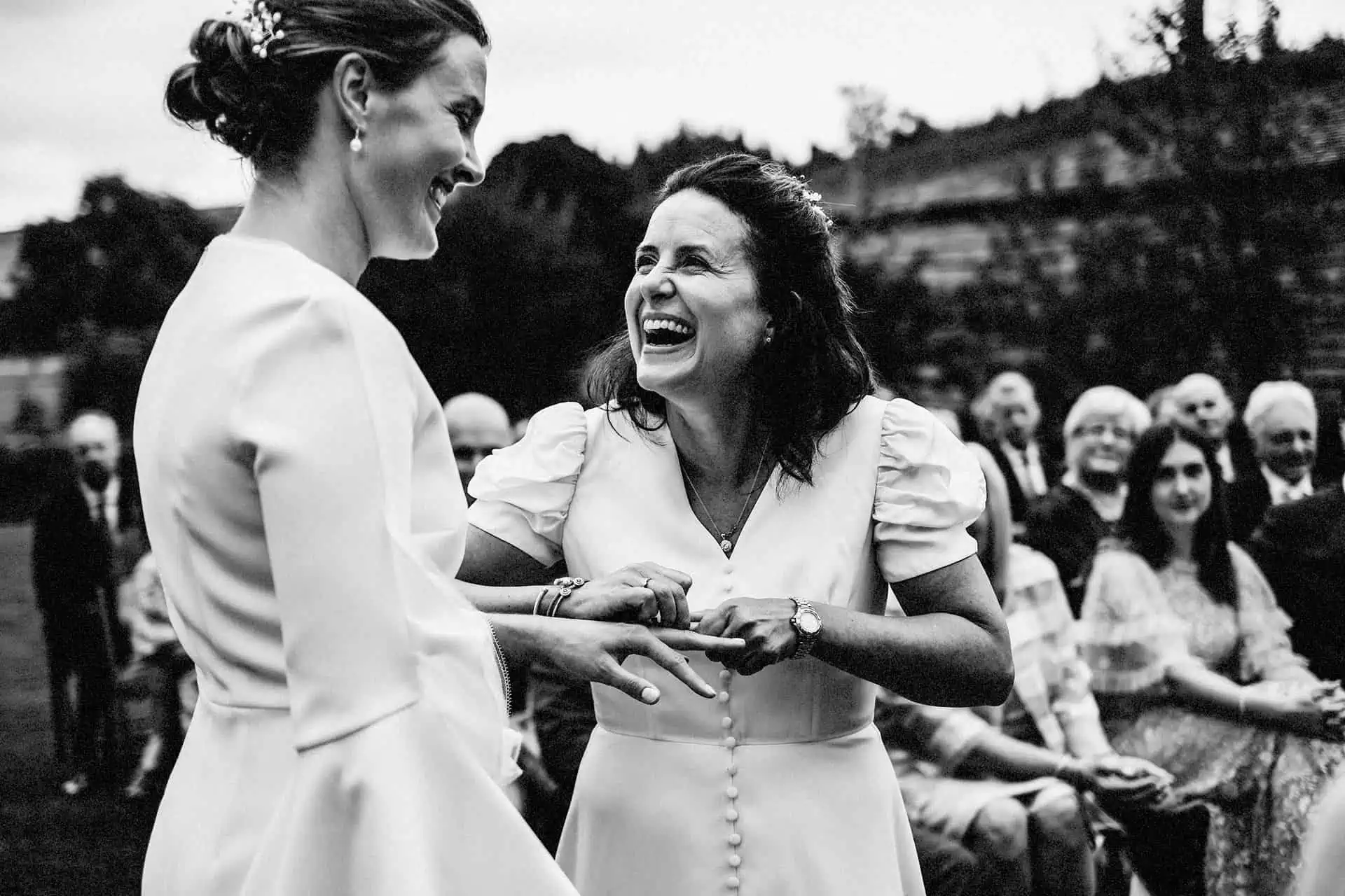 two brides laughing as they exchange wedding rings in outdoor ceremony at the lord crewe arms by same sex wedding photographer in newcastle upon tyne and county durham andy turner