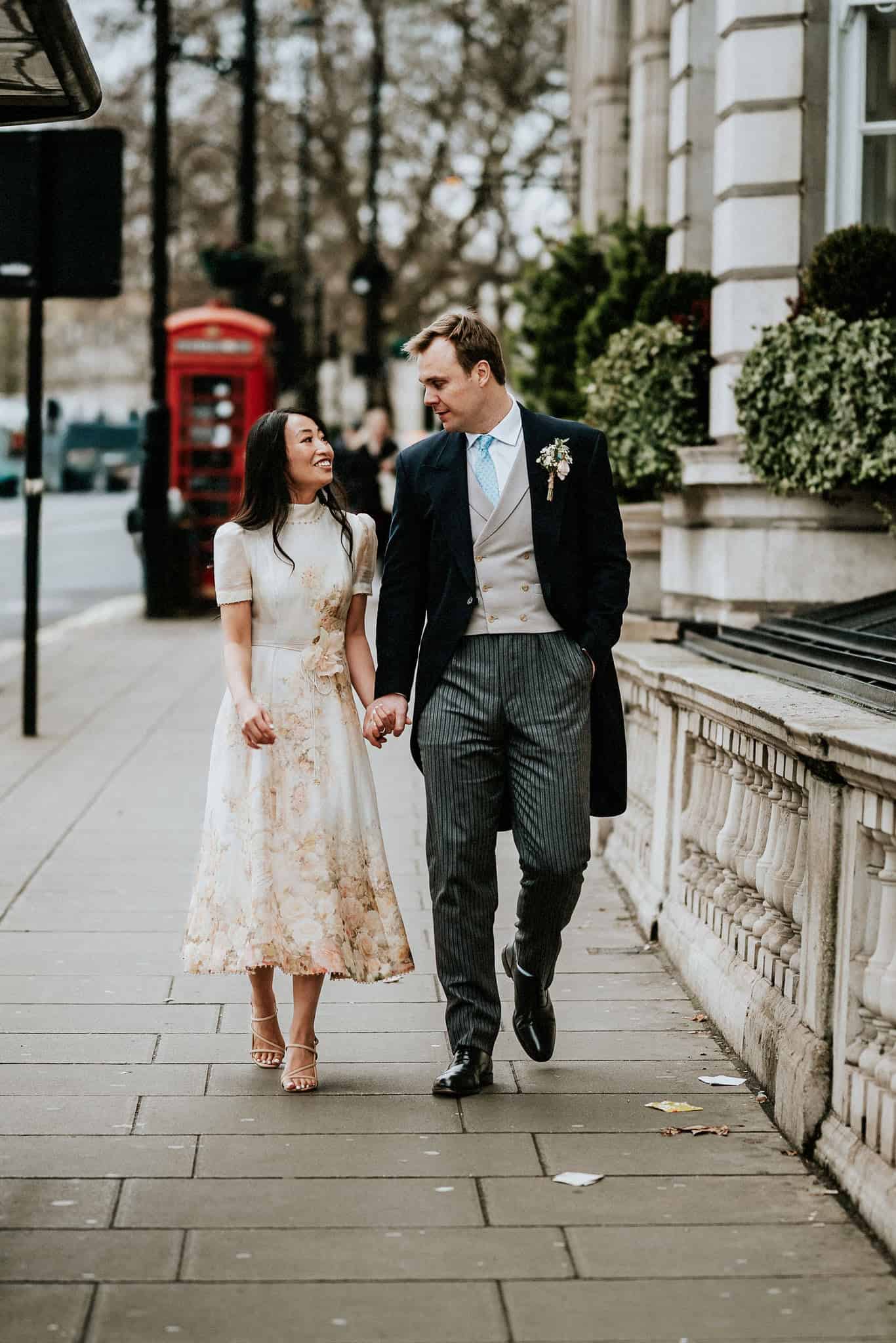 Bride and groom walking by the Cavalry & Guards Club by UK wedding photographer Andy Turner